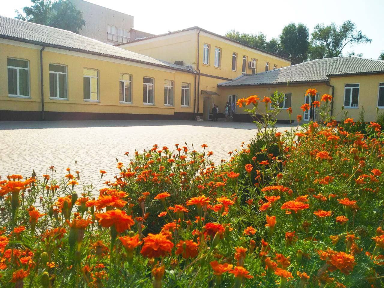Подвір'я ліцею: жовта будівля, вимощений двір і клумба з чорнобривцями